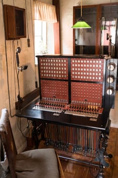 A classic vintage telephone switchboard, showcasing the history of communication technology. Set in an authentic period interior with wood furnishings and a green lamp