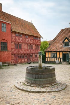 arhus,denmark,An old European courtyard featuring traditional half-timbered buildings and a stone fountain, evoking historical charm and cultural heritage from a bygone era.