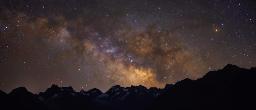 The galactic core of the Milky Way paints a vibrant backdrop above the silhouetted peaks of towering mountains.