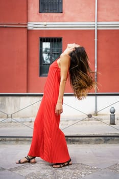 A young woman dressed in a stunning red dress strikes a graceful pose against a vibrant and colorful backdrop, perfectly showcasing both elegance and beauty as she moves gracefully through the scene