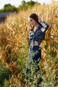 A young woman stands with grace and poise among the vibrant golden corn stalks, dressed in a very stylish outfit that beautifully captures and showcases the delightful beauty of nature all around her