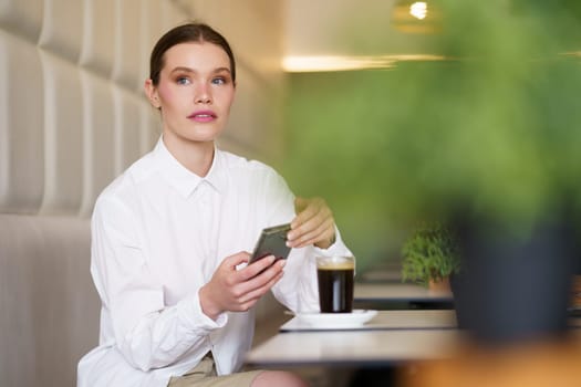 Elegant beauty businesswoman working with mobile phone sitting in a cafeteria with a glass of coffee at night
