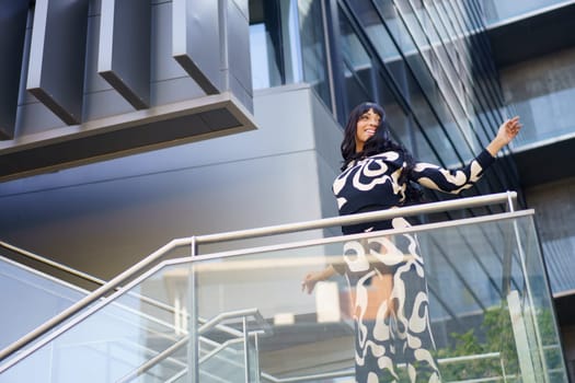 Low angle view photo of a female caucasian cool artist dancing energetically from the stairs of a modern building
