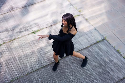 Top view of a happy female caucasian dancer performing a choreography dressing black summer dress outdoors