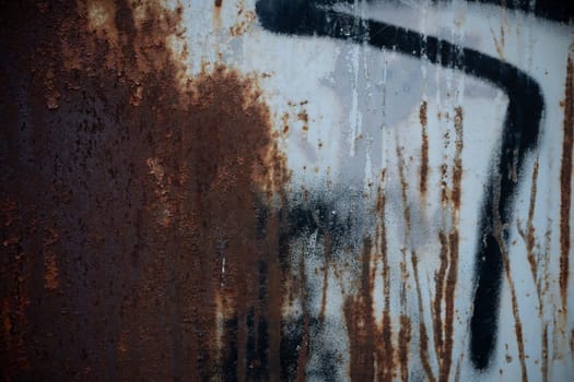 A rusty metal wall providing a textured and weathered background with black paint