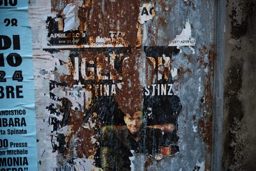 Cremona, Lombardy, Italy October 15th 2024 Weathered advertising posters are peeling from a rusty metal surface, creating an abstract composition