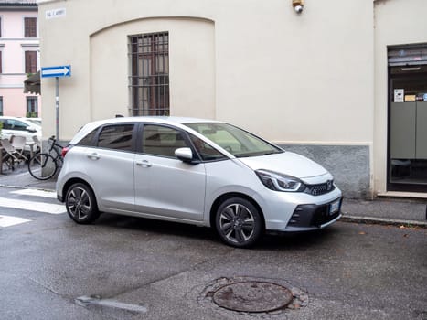 Cremona, Lombardy, Italy October 15th 2024 Modern silver honda jazz parked on the sidewalk by a crosswalk in a typical european urban setting