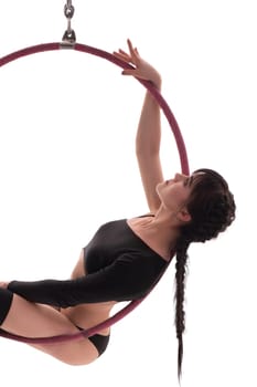 Side view of beautiful charming gymnast sitting on hung hula hoop on white background
