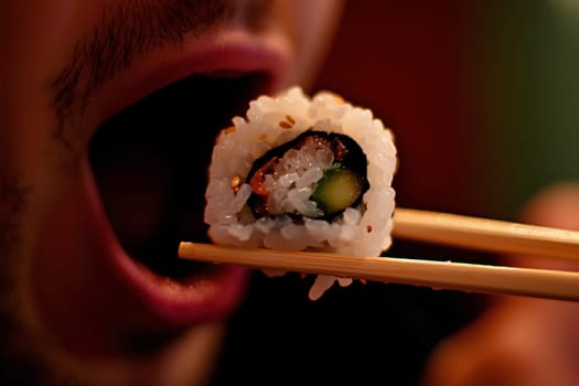 a man uses chopsticks to hold a sushi roll she is about to eat, Japanese food photo for menu..