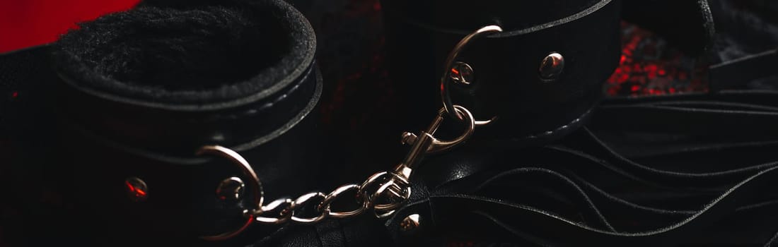 Handcuffs and a whip with women's sexy underwear. Concept of sex toys for BDSM with submission and domination. Panoramic wide horizontal photo for banner head cover