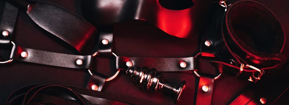 Female set of sex toys from a sex shop for BDSM sex with submission and domination. Mask, leather belt, choker, handcuffs, whip and anal plug. Panoramic wide horizontal photo for banner head cover