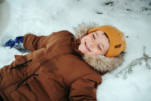 happy baby child boy lies in a snowdrift in snow in the winter