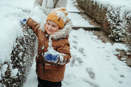 Happy little child boy playing in the park in winter