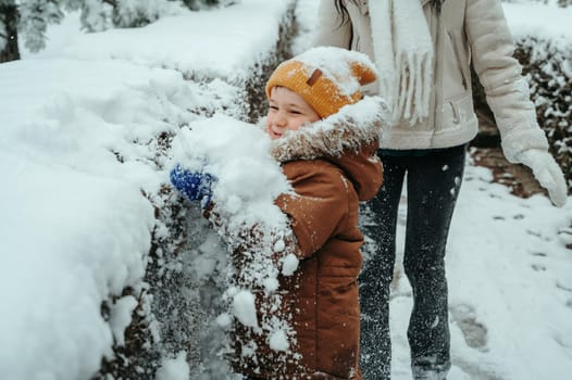 Happy little child boy playing in the park in winter
