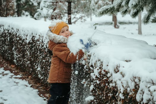 Happy little child boy playing in the park in winter