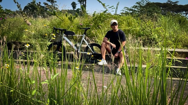 Healthy lifestyle, bicycle sport and exercise, a man in casual sportswear rides a bicycle on a sunny day surrounded by lush greenery, the image captures a sense of relaxation and outdoor adventure, good for health and sport article or content creation