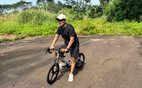 Healthy lifestyle, bicycle sport and exercise, a man in casual sportswear rides a bicycle on a sunny day surrounded by lush greenery, the image captures a sense of relaxation and outdoor adventure, good for health and sport article or content creation