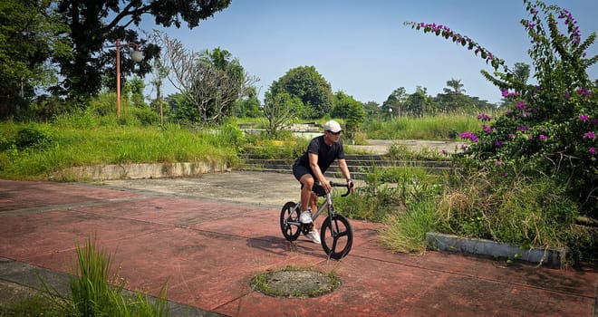 Healthy lifestyle, bicycle sport and exercise, a man in casual sportswear rides a bicycle on a sunny day surrounded by lush greenery, the image captures a sense of relaxation and outdoor adventure, good for health and sport article or content creation