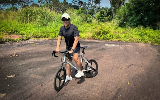 Healthy lifestyle, bicycle sport and exercise, a man in casual sportswear rides a bicycle on a sunny day surrounded by lush greenery, the image captures a sense of relaxation and outdoor adventure, good for health and sport article or content creation