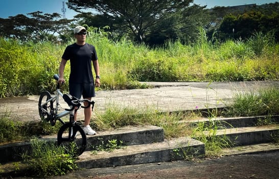 Healthy lifestyle, bicycle sport and exercise, a man in casual sportswear rides a bicycle on a sunny day surrounded by lush greenery, the image captures a sense of relaxation and outdoor adventure, good for health and sport article or content creation