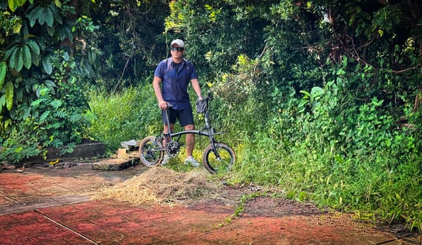 Healthy lifestyle, bicycle sport and exercise, a man in casual sportswear rides a bicycle on a sunny day surrounded by lush greenery, the image captures a sense of relaxation and outdoor adventure, good for health and sport article or content creation