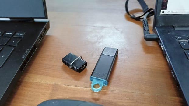 black Flashdrives placed on a table between two laptops