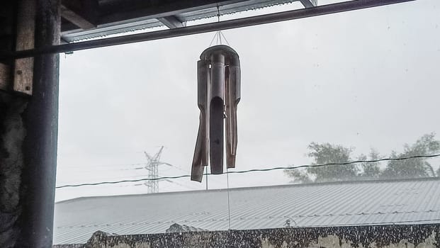 A wooden wind chimes showcasing various cylindrical tubes and circular pendants, creating soothing sounds when swayed by the wind.