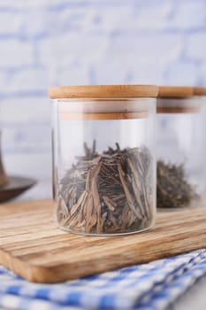 Dry tea leaves in a jar on table .