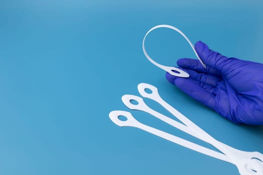 Flexible Plastic Tongue Scraper, Cleaner Tool In Hand Of Dentist In Blue Glove On Blue Background. Oral Care Scraper, Hygiene. Healthy Teeth And Mouth. Space For Text, Horizontal. High quality photo