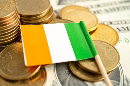 Stack of coins with Ireland flag and US dollar banknotes.