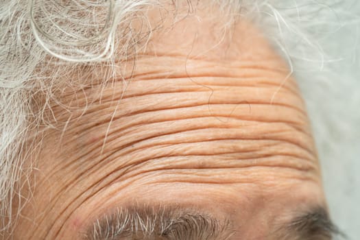 Asian elderly woman face and eye with wrinkles, portrait closeup view.