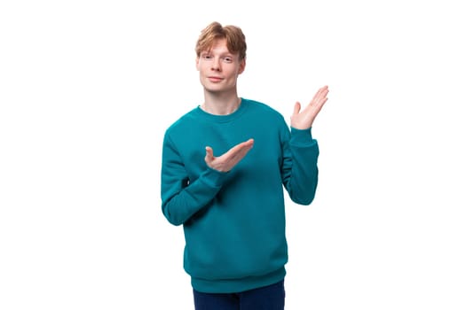 caucasian young red-haired guy dressed in a blue pullover points with his hand. advertising concept.