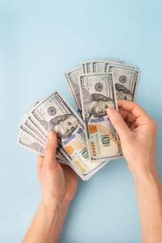 Female hands counting 100 dollar bills isolated on a blue background