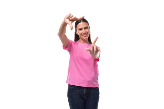 young smart slender woman dressed in a pink cotton t-shirt takes a photo with her hands.