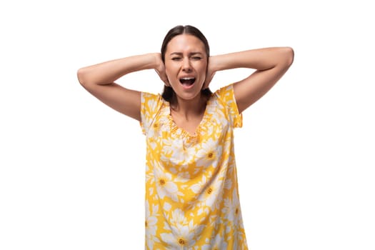 close-up portrait of a young caucasian woman in a yellow summer t-shirt with closed ears and screaming.