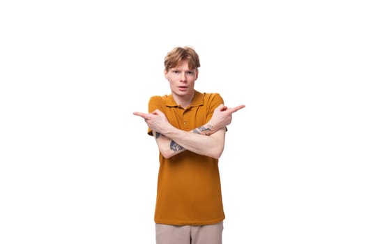 a young handsome red-haired man with a haircut and a tattoo on his arm is dressed in a summer yellow t-shirt.