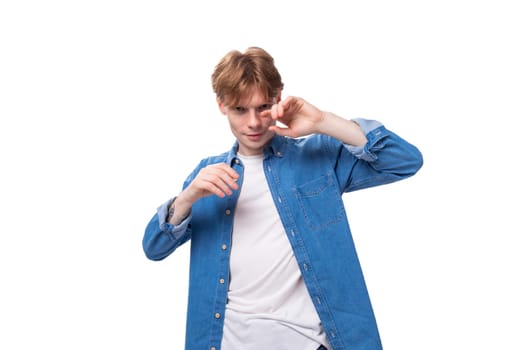 young caucasian red-haired man in a denim shirt posing on a white background with copy space.