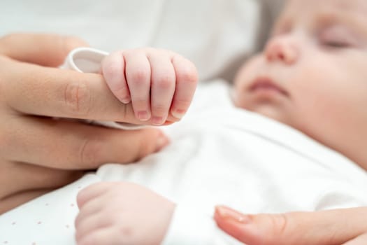 Close-up reveals a newborn baby holding mother's hand, a symbol of security and maternal affection