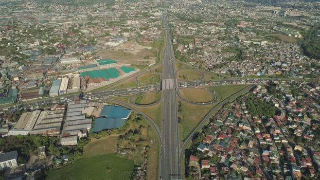 Aerial view of highway with road junction, car and traffic in Manila, Philippines. Highway in Manila among residential buildings. View of highway intersection.