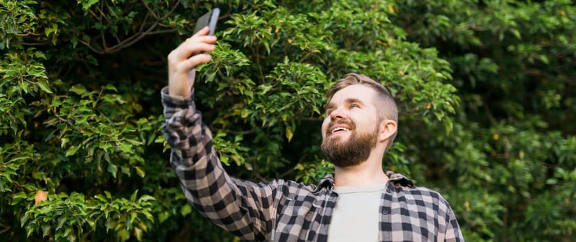 Man taking selfie portrait over palm tree background - Happy millennial guy enjoying summer holidays in city - Youth and technologies.