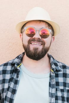 Portrait handsome man wearing summer hat and plaid shirt smiling happy near wall - travel vacations and summer holiday