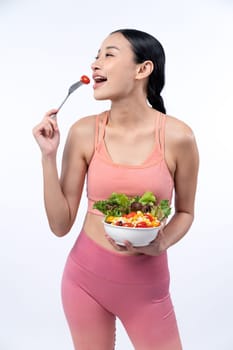 Young sporty Asian woman in sportswear holding salad bowl fill with vibrant of fruit and vegetable. Natural youthful and fit body lifestyle with balance nutrition on isolated background. Vigorous