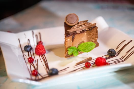 delicious chocolate cheesecake in a coffee shop. serving dessert on a white plate with berries.