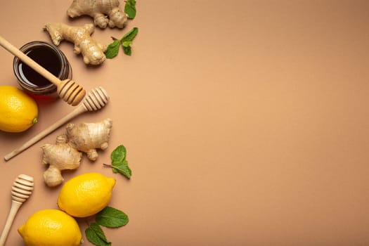 Orange detox drink, lemons, mint, ginger, honey in glass jar, honey wooden dippers top view. Food for immunity stimulation and against flu. Healthy remedies to boost immune system, copy space.