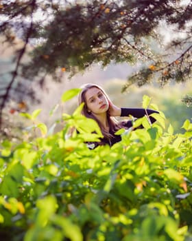 Beautiful girl in green foliage in the autumn park