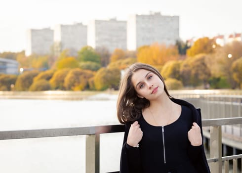 Portrait of a girl on a bridge near a pond in a city park