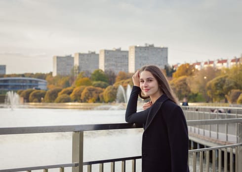 Portrait of a girl on a bridge near a pond in a city park