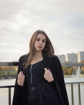 Portrait of a girl on a bridge near a pond in a city park