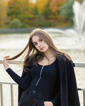 Portrait of a girl on a bridge near a pond in a city park