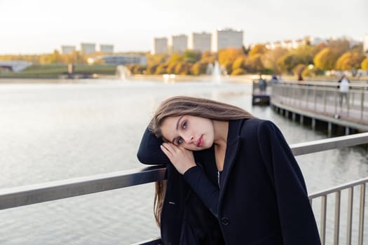 Portrait of a girl on a bridge near a pond in a city park against the backdrop of fountains